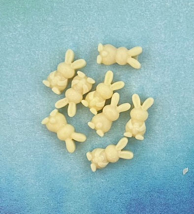 Eight cream-colored bunny-shaped soy wax melt candles displayed on a light blue flat surface, radiating a calm and serene aesthetic perfect for cozy, tranquil moments.