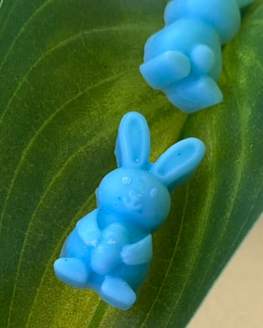Two ocean-colored bunny-shaped soy wax melts on top of a green leaf, showcasing a playful and vibrant design.