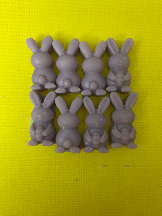 Eight purple bunny-shaped soy wax melt candles arranged on a bright yellow flat surface, creating a vibrant and cheerful display that embodies playful and uplifting vibes.
